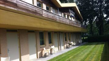 Un hotel con un área de estar al aire libre cubierta, múltiples ventanas y un césped bien cuidado.