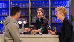 Een bar, met flessen en glazen op de planken.
