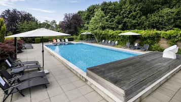 Una piscina rectangular con cubierta de madera y sillas de descanso.
