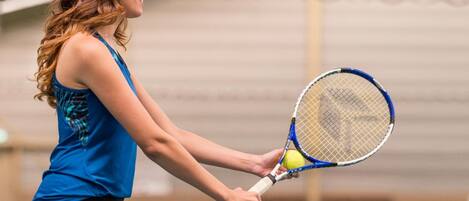 A person holding a tennis racket and a tennis ball.