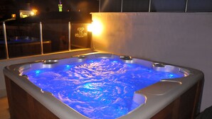 A hot tub with a blue light feature, surrounded by a wooden deck and a glass enclosure. - Divani Ali Hotel (Istanbul)