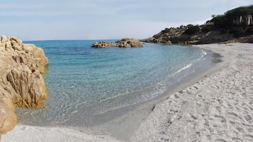 Una playa con agua cristalina, formaciones rocosas y una orilla arenosa.