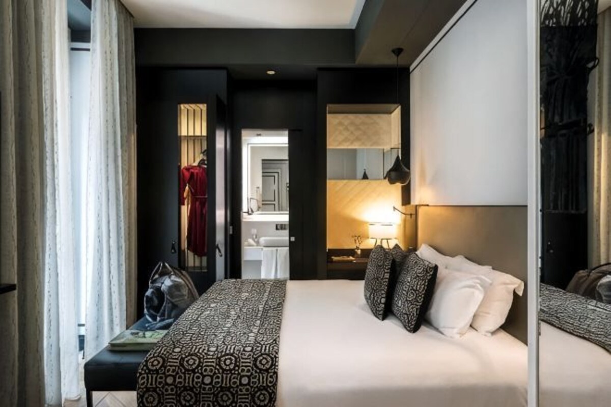 Une chambre d’hôtel avec un lit, une table de chevet, une lampe et un miroir.