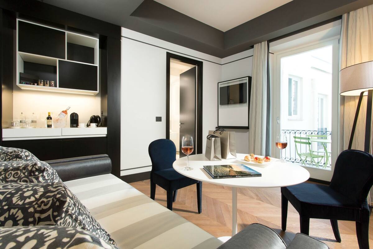 Une chambre d’hôtel moderne équipée d’un canapé, de deux fauteuils, d’une table à manger, d’un téléviseur et d’un balcon avec vue.