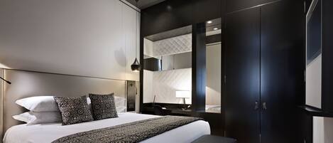 Un dormitorio moderno con una cama grande, un banco, un armario y un espejo.