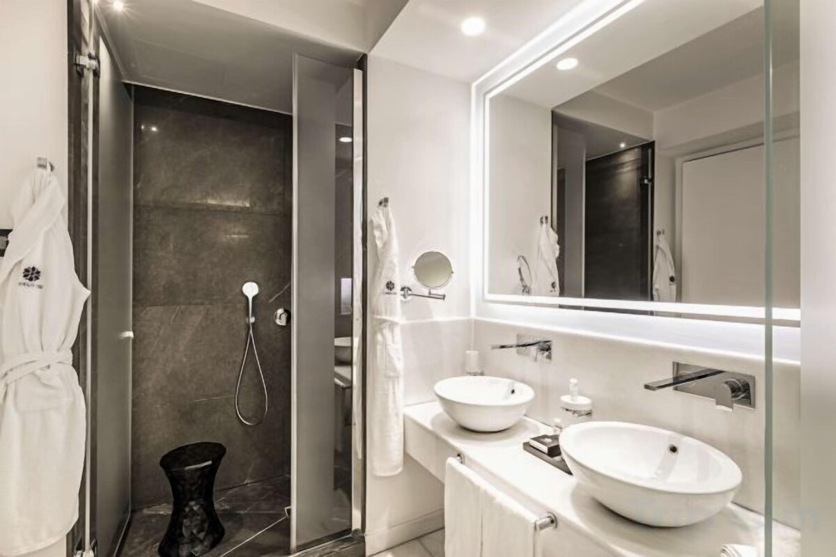 A modern bathroom with a glass shower enclosure, a double sink vanity, and a large mirror.