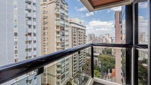 Un edificio alto con varios balcones, grandes ventanales y vistas a otros edificios.