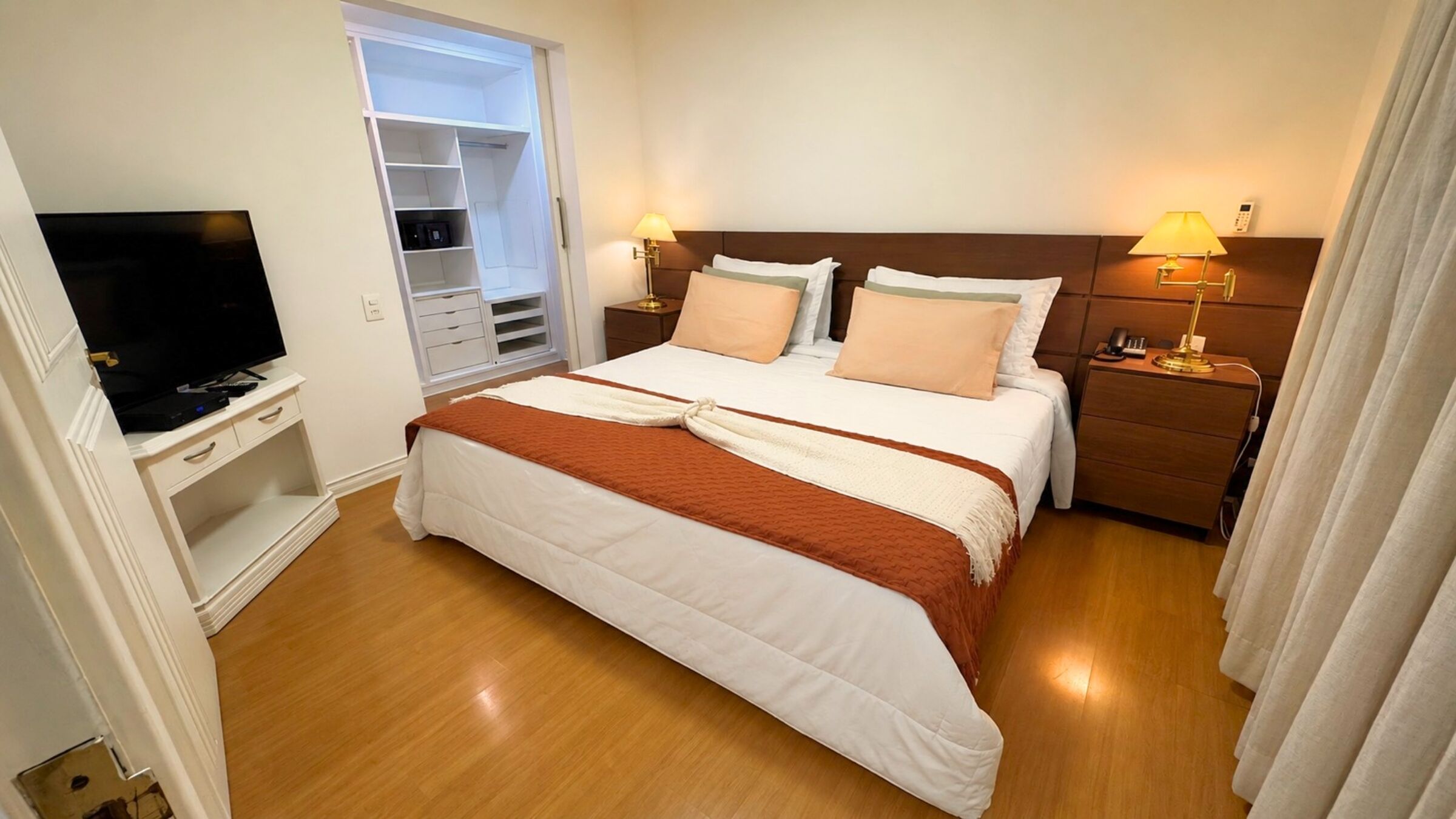 Ein Hotelzimmer mit Bett, Nachttischen, Fernseher, Kleiderschrank und Bad.