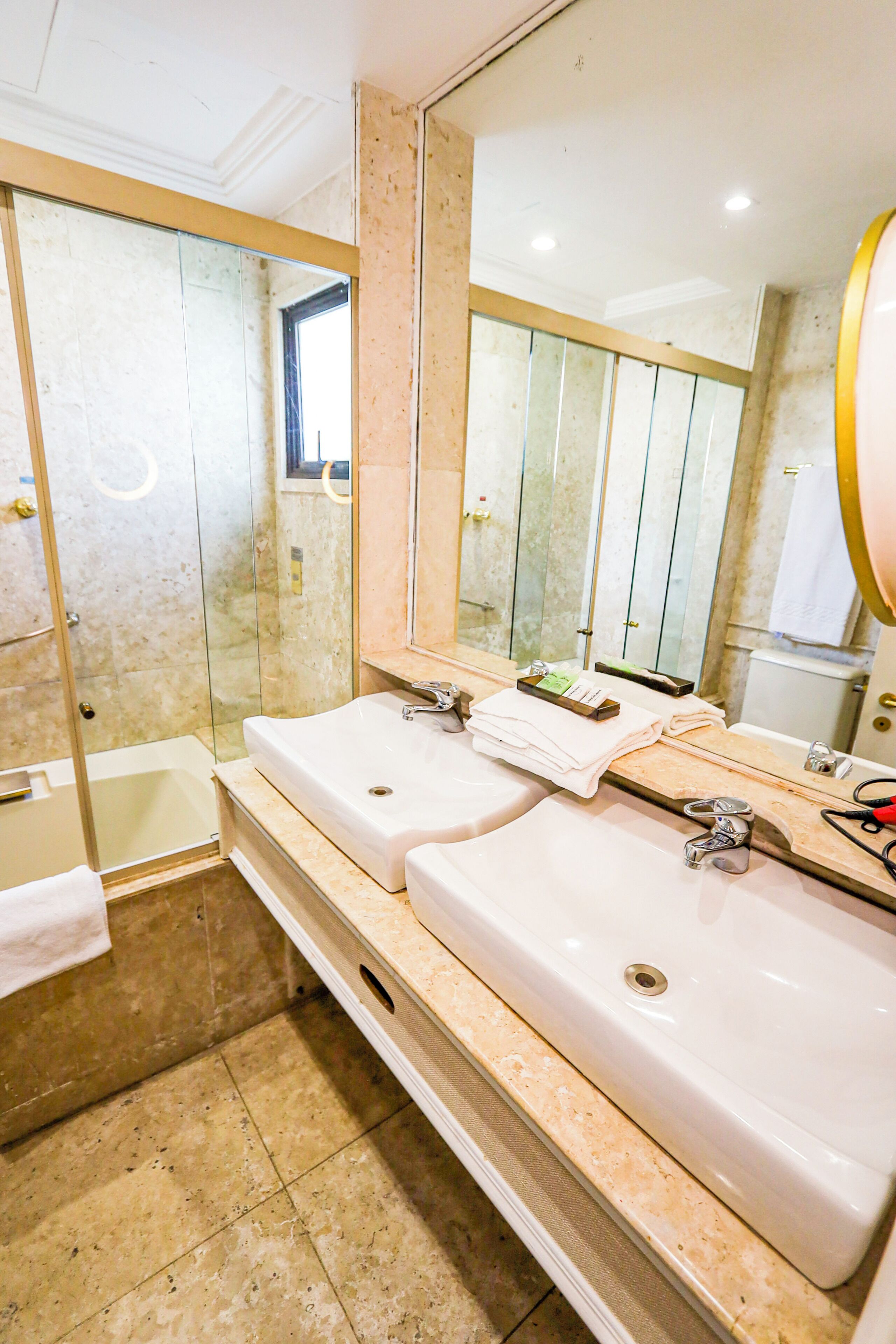 A bathroom with two sinks, a mirror, a shower, and a towel rack.