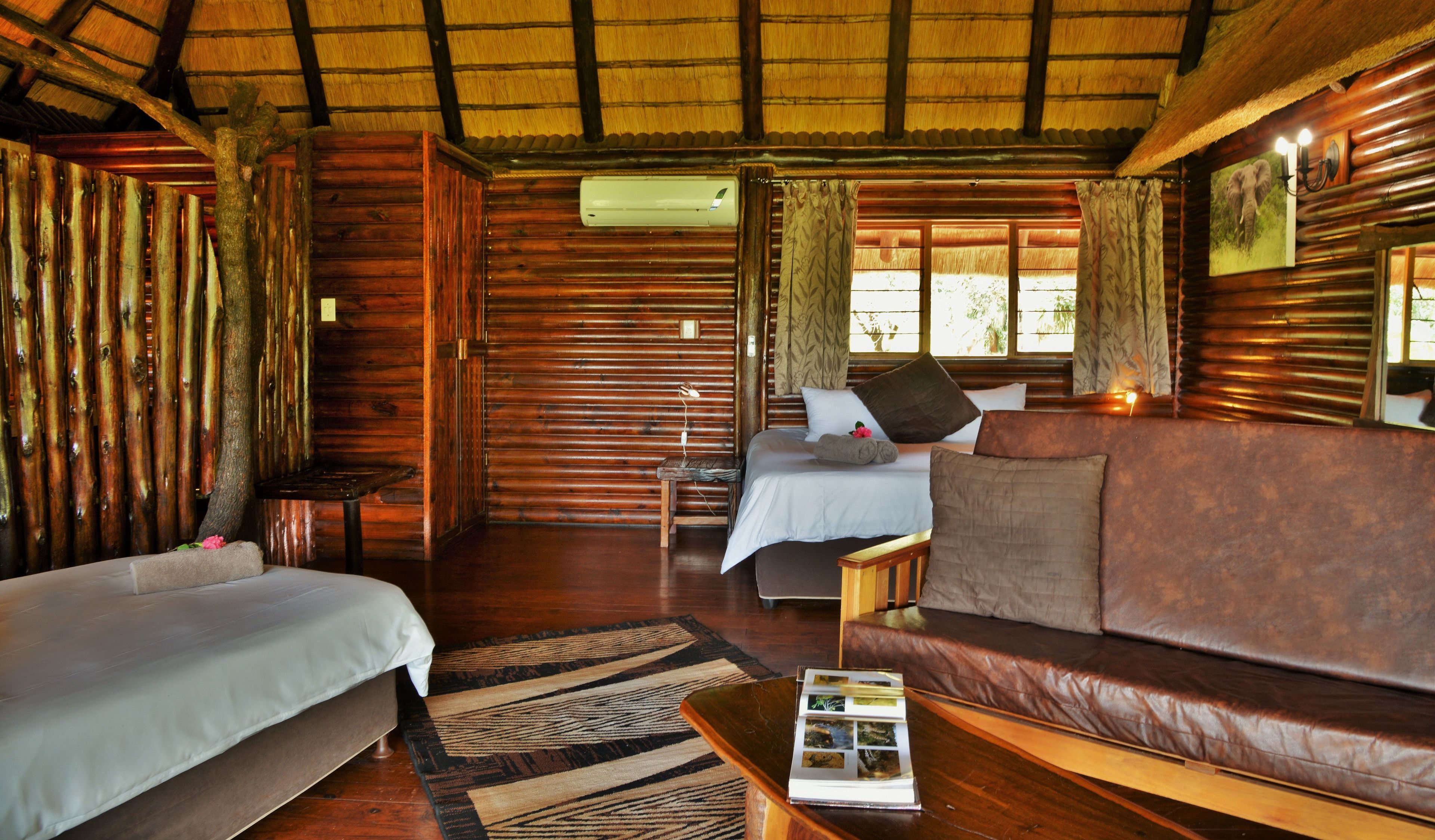 Una habitación con paredes de madera, una cama, un sofá y una mesita con una revista.