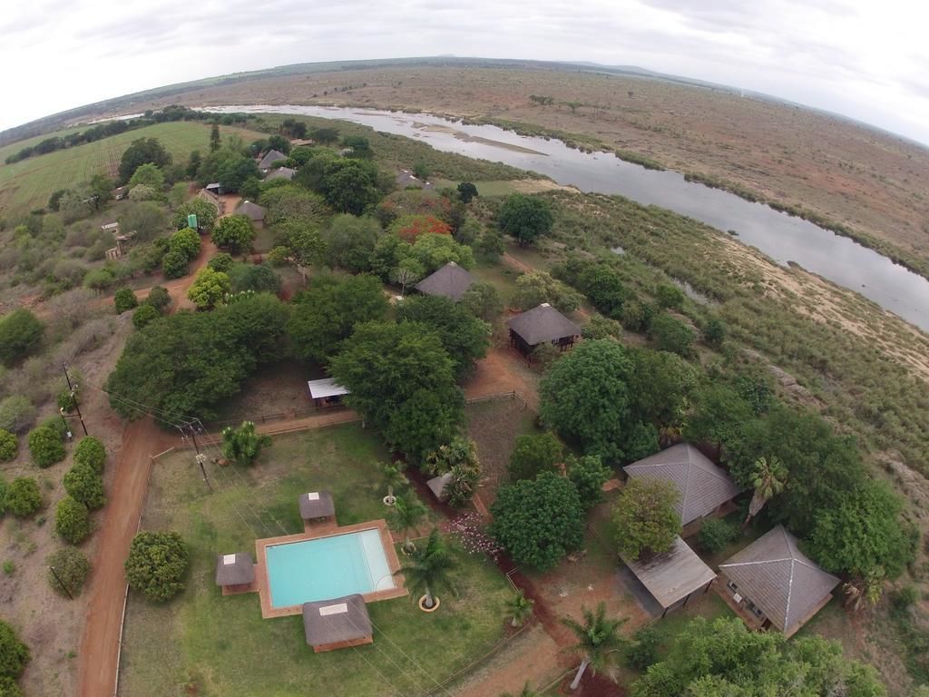 An aerial view of a property with a swimming pool, multiple houses, and a river.