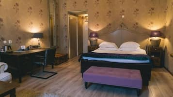 A bedroom with a bed, bedside lamps, a desk, and a chair.