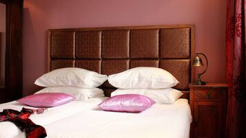 A neatly made bed with white and pink pillows, a wooden headboard, and a bedside table with a lamp.
