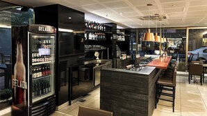 Un área de bar moderna con un refrigerador negro, estantes llenos de botellas y una barra de madera.