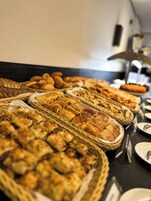 Una mesa de buffet con panes y pasteles varios en cestas de mimbre.