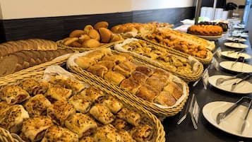 A buffet with various types of bread and pastries.