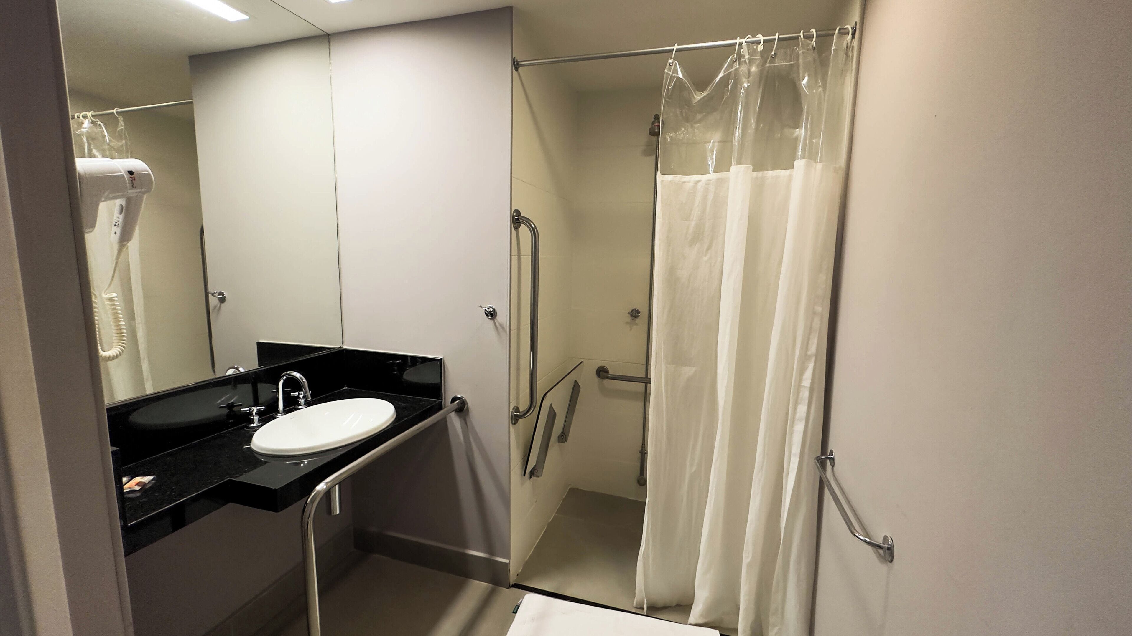 A modern bathroom with a black countertop sink, a white mirror, and a glass shower enclosure.
