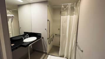 Un baño moderno con lavamanos de encimera negro, espejo blanco y cabina de ducha de vidrio.