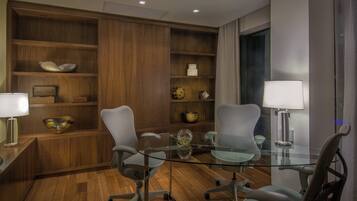 A modern meeting room with glass tables, office chairs, wooden shelving, and lamps.