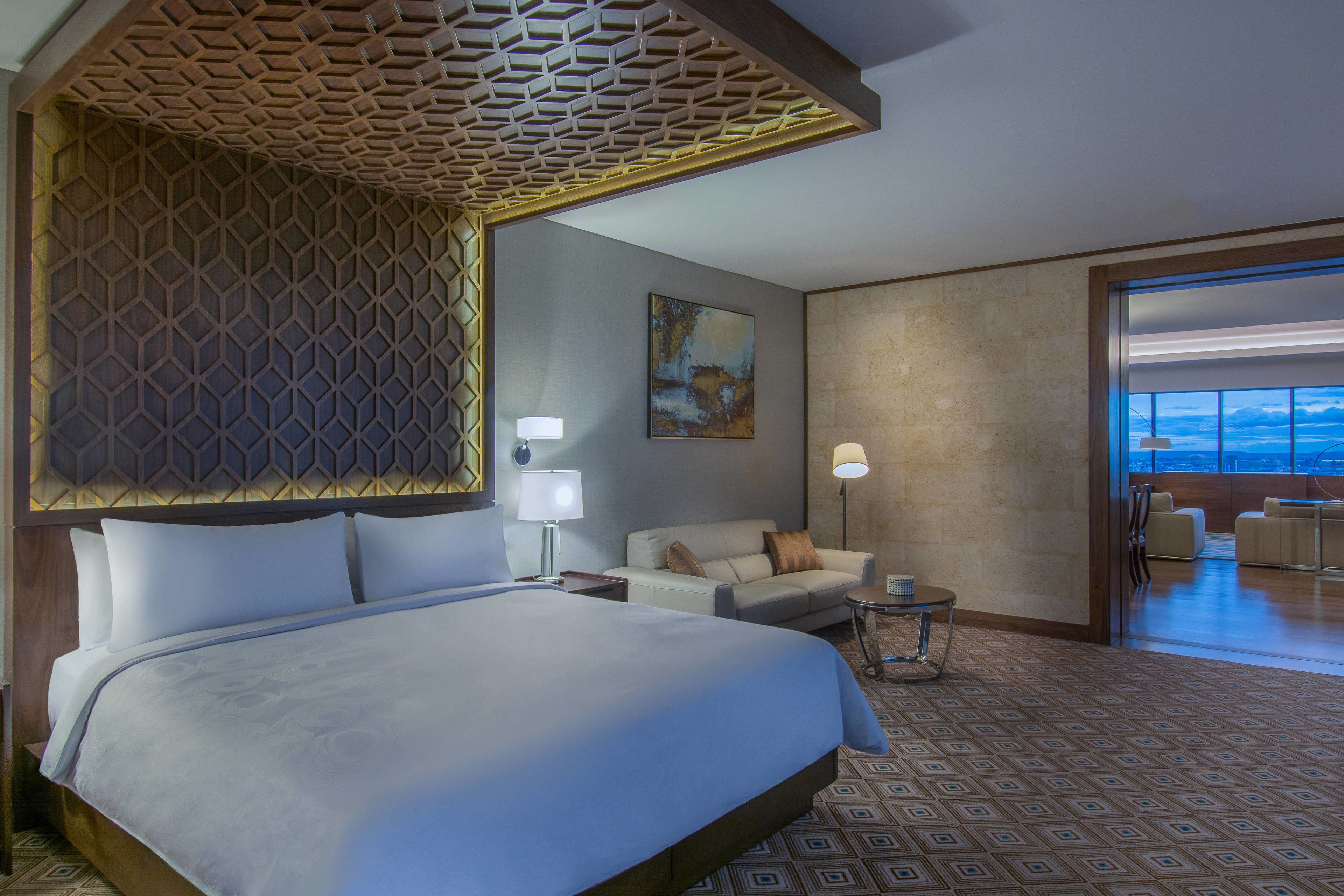 Een hotelkamer met een groot bed, een bank, een bijzettafeltje en uitzicht op het groen.
