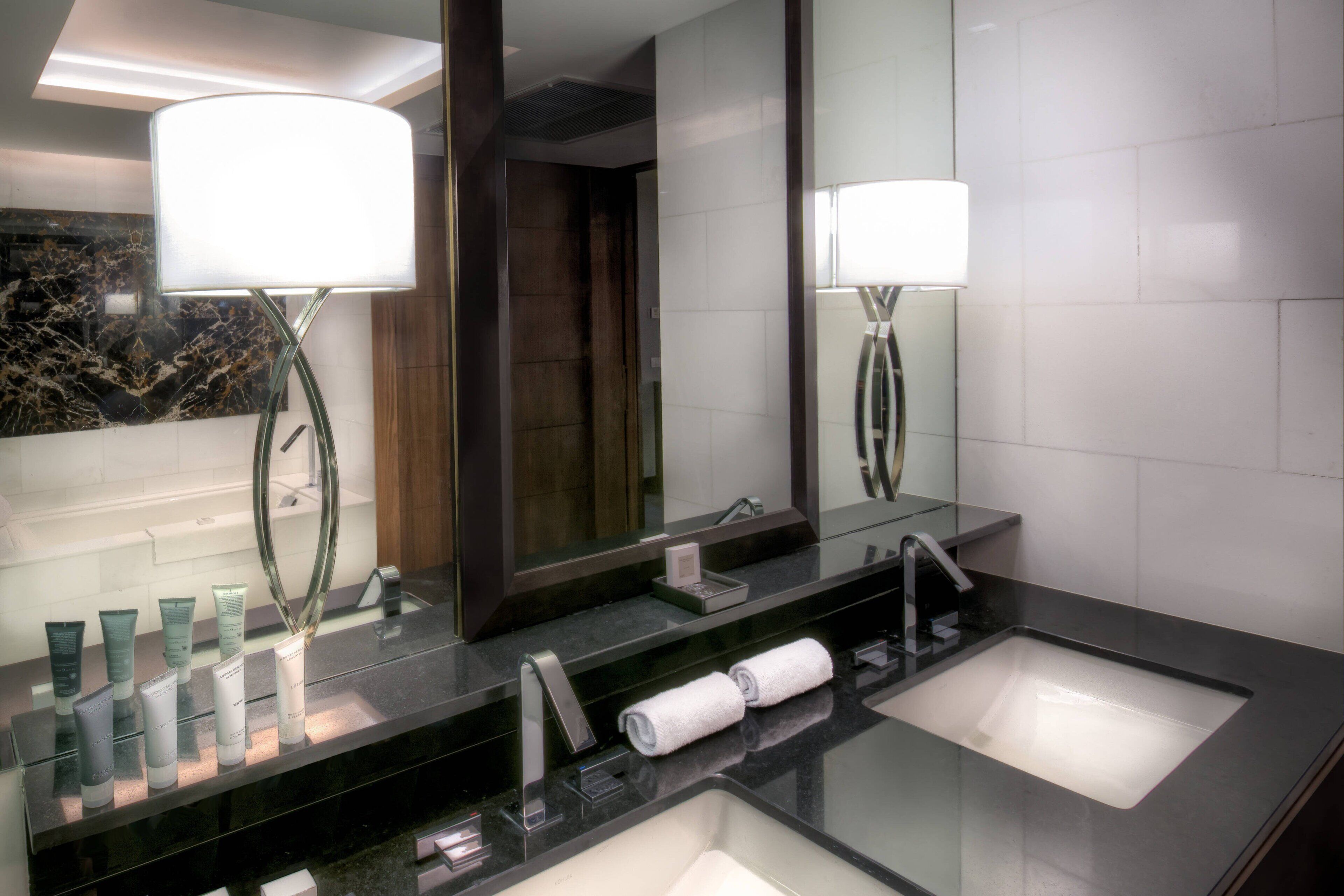 Ein modernes Badezimmer mit zwei Waschbecken, einem großen Spiegel und einem Waschtisch mit Hautpflegeprodukten.