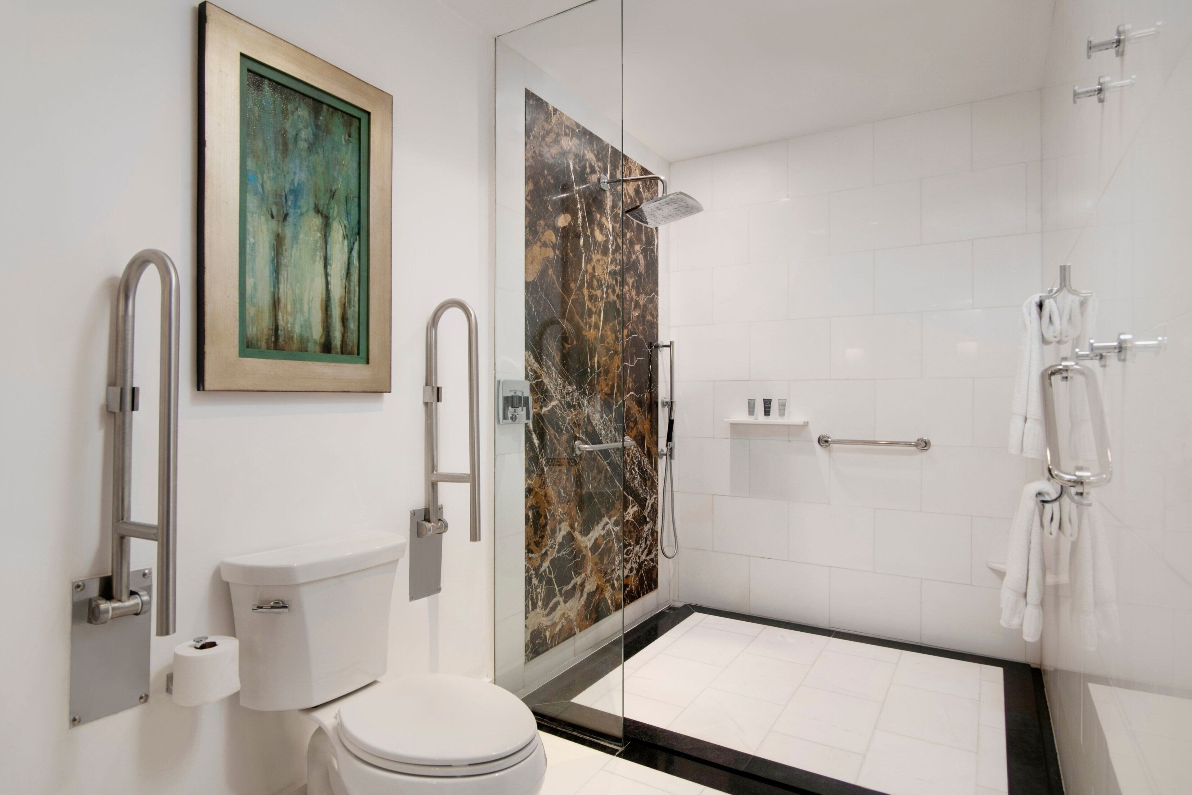 Un baño moderno con inodoro, ducha con mampara de vidrio y pared de mármol.
