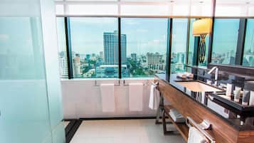 A modern bathroom with a large window, a wooden vanity, and a city view.
