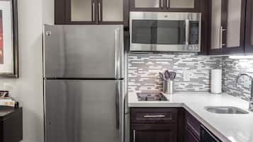Una cocina moderna con electrodomésticos de acero inoxidable, un salpicadero de azulejos y muebles de cocina oscuros.