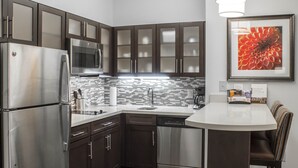Una cocina moderna con electrodomésticos de acero inoxidable, armarios de madera oscura, salpicadero de azulejos y una zona de comedor con banco.