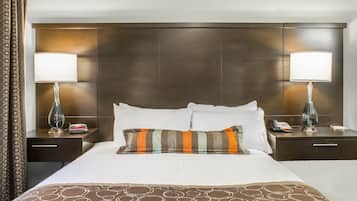 Habitación de hotel con una cama grande, dos mesitas de noche, una lámpara, un teléfono y una colcha estampada.