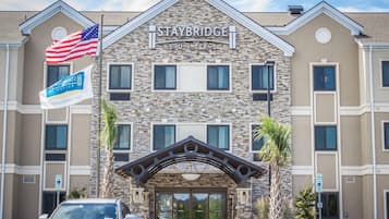 A Staybridge Suites hotel with a stone facade, multiple windows, and a flagpole with the American flag.