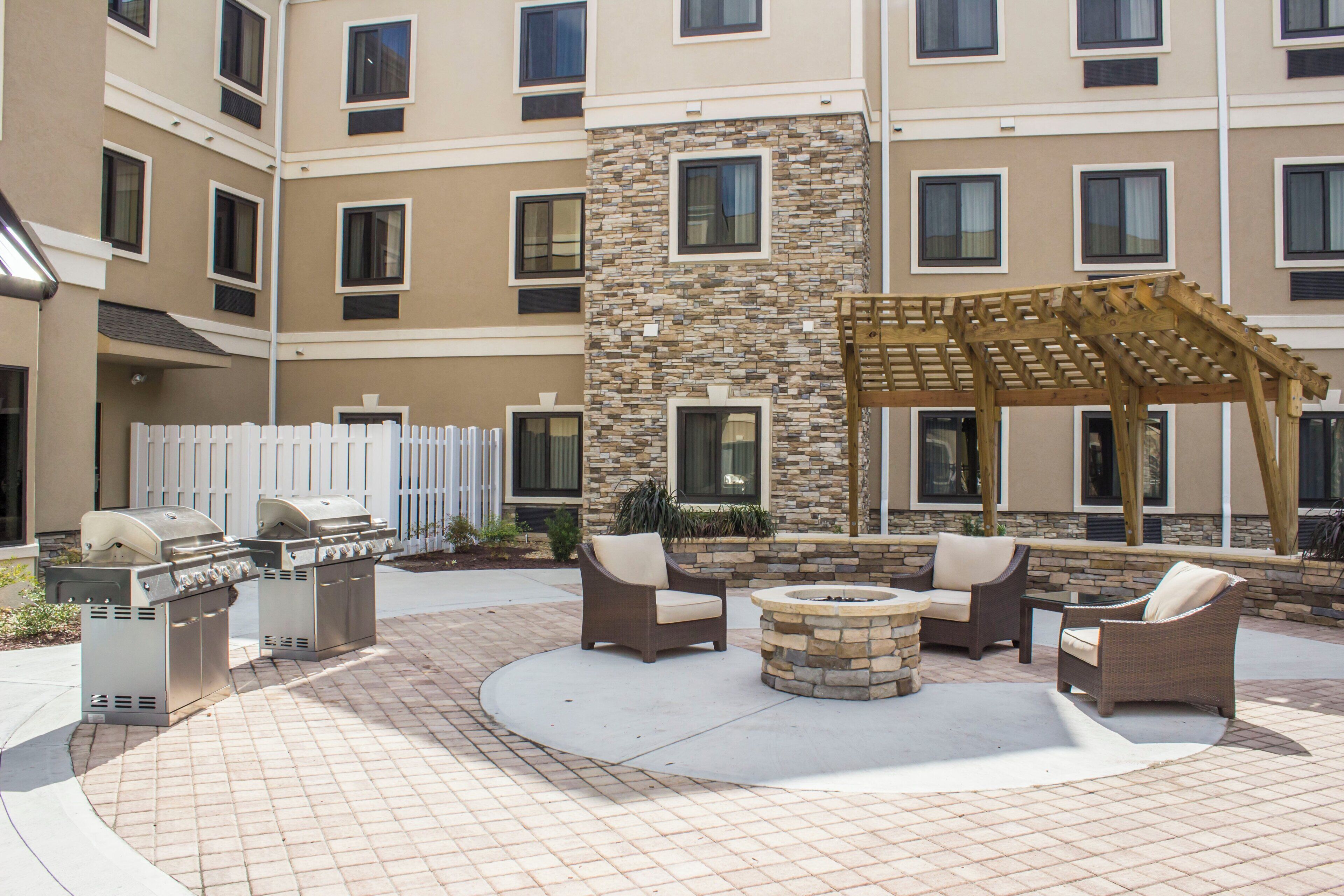 Un patio con mobiliario exterior, una parrilla y una chimenea de piedra.