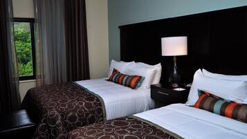 A hotel room with two beds, a nightstand with a lamp, and a window with curtains.
