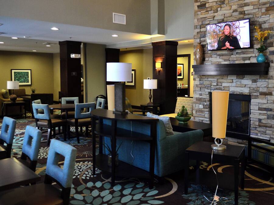 A hotel lobby with a television mounted on a stone wall, seating arrangements, and a fireplace.