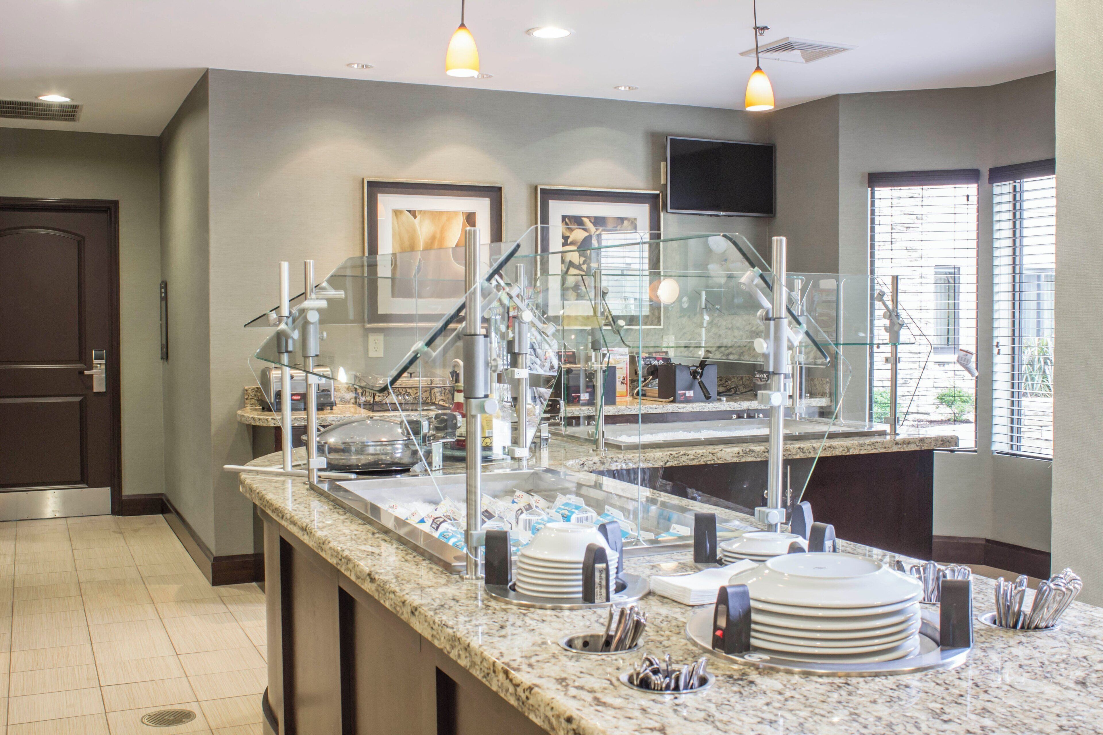 A buffet area with a glass partition, stainless steel appliances, and a flat-screen TV mounted on the wall.