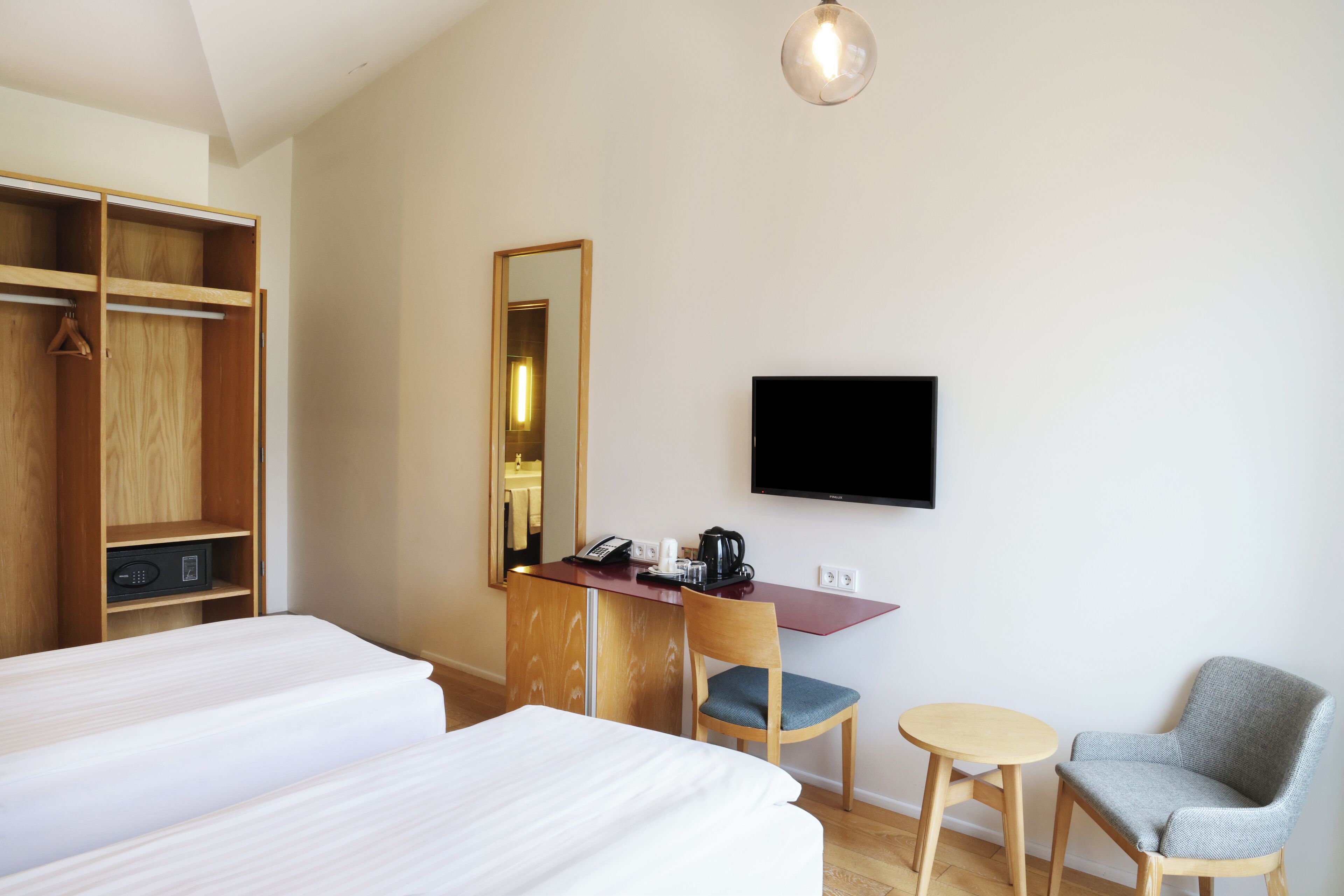 Una habitación de hotel con dos camas, un escritorio con silla, un televisor y un armario.