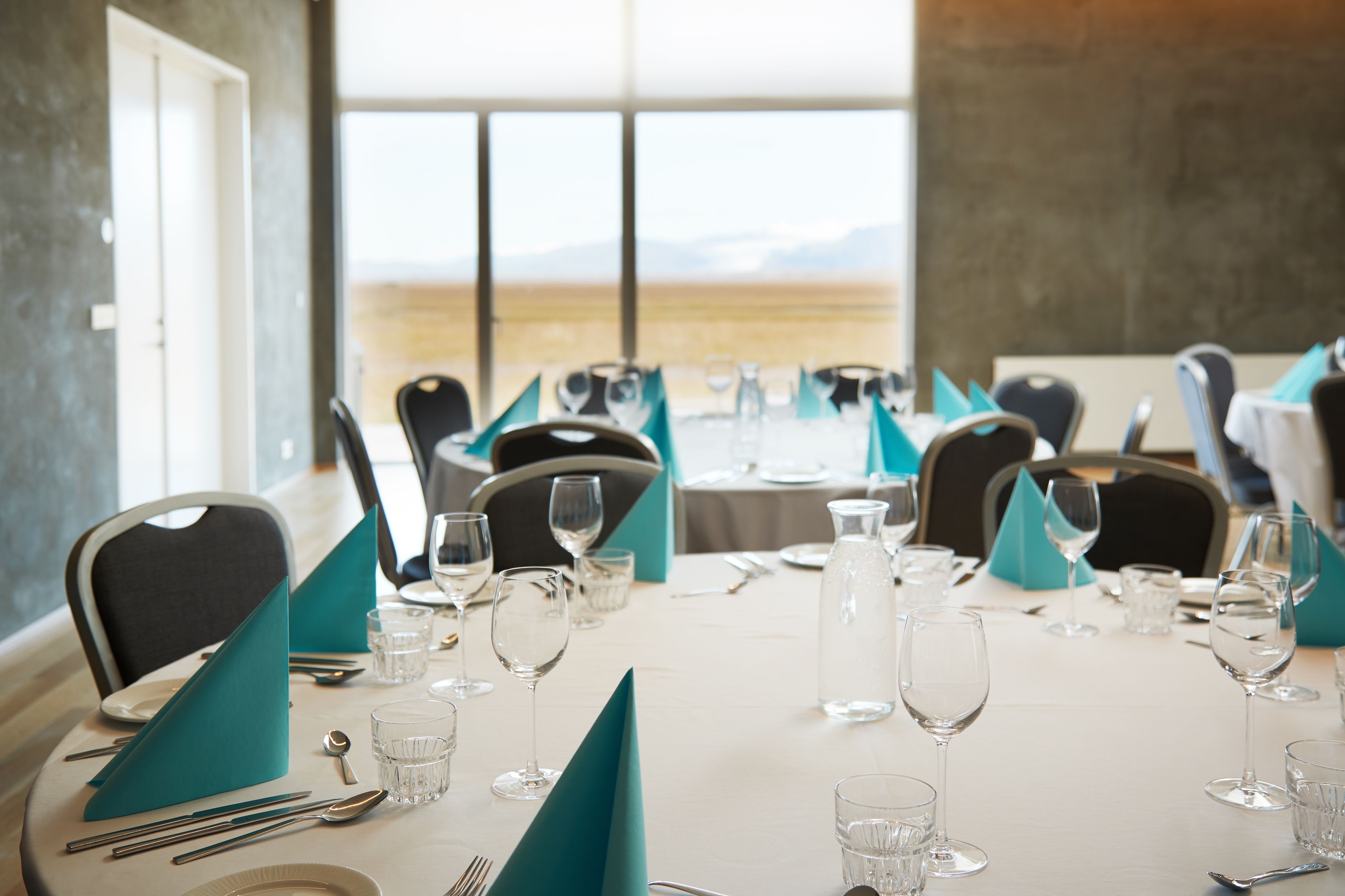 A dining table set for a meal with chairs, glasses, and cutlery.