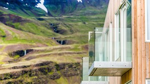 Um edifício moderno com grandes janelas de vidro e vista para uma paisagem montanhosa.