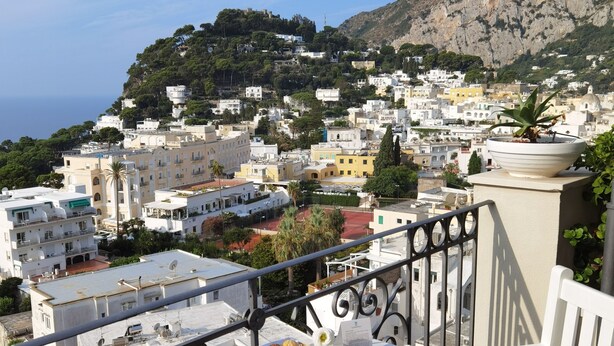 Une table sur un balcon, avec un petit-déjeuner et une vue sur une ville côtière.
