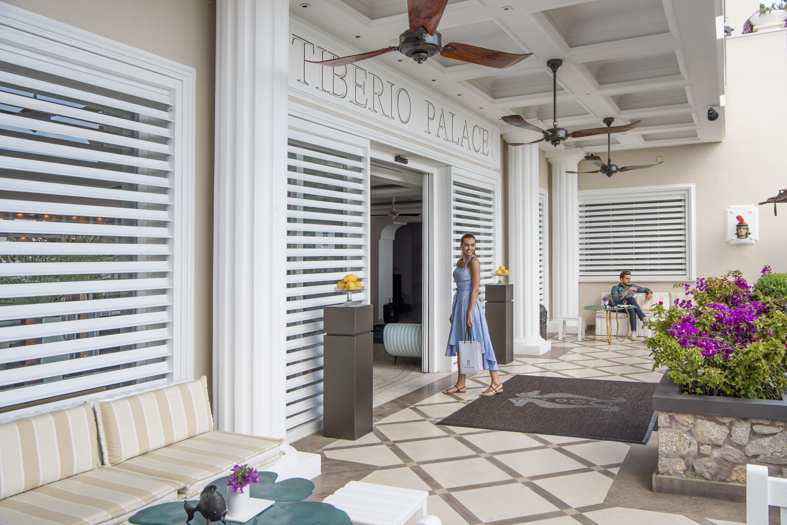 A hotel entrance with a sign reading "HIBERIO PALACE," a tiled floor, and a seating area with a sofa and a table.