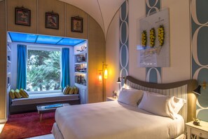 A hotel room with a large bed, a window seat with curtains, a map on the wall, and a map of Capri.