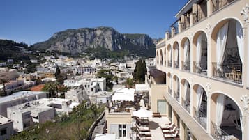 Un hotel con varios balcones, piscina y vistas a un paisaje montañoso.