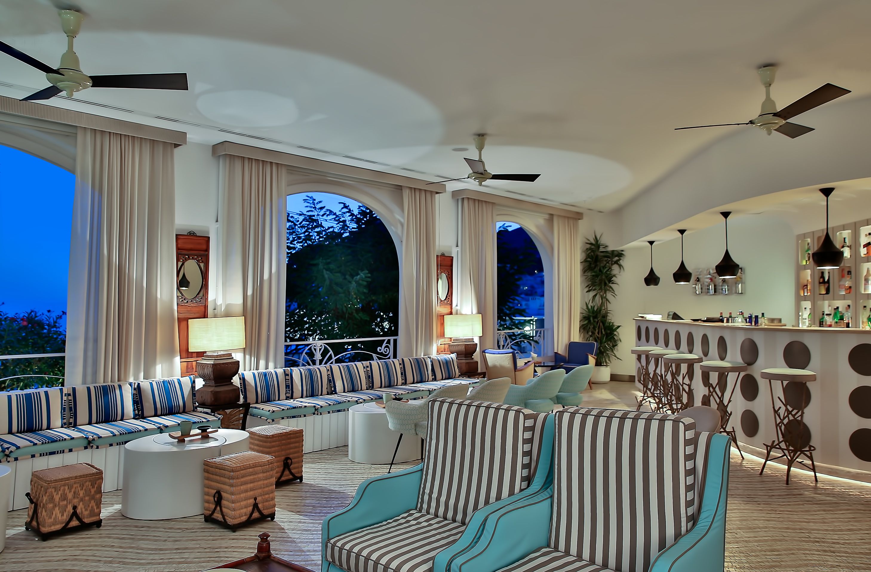 Amplia sala de estar con bar, asientos y grandes ventanales con vistas al exterior.