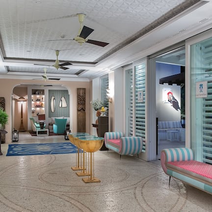 A modern hotel lobby with a central seating area, ceiling fans, and a glass partition wall.