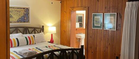 Una habitación acogedora con una cama, un sillón verde, una mesita y paneles de madera.