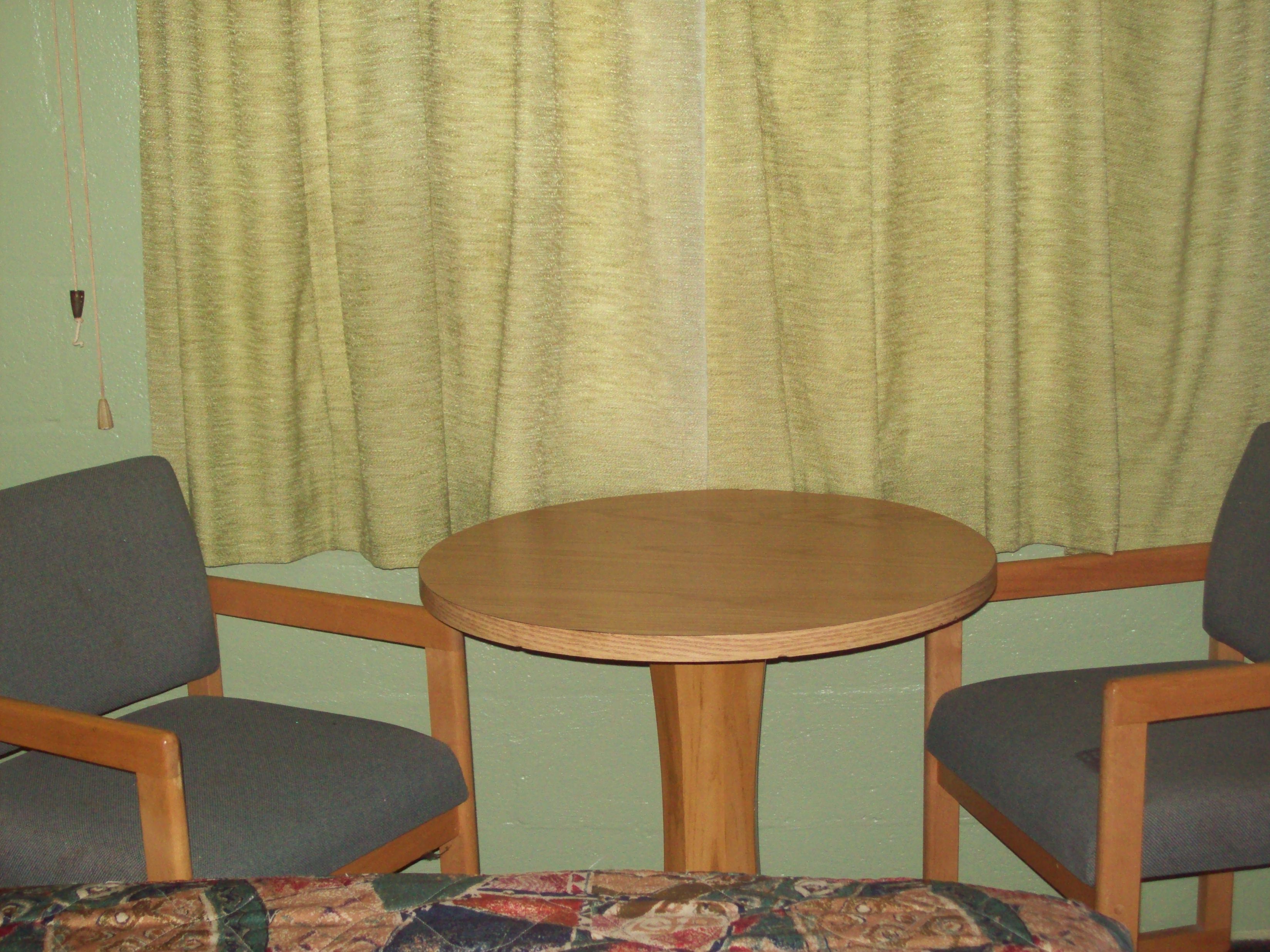 A room with a round wooden table and two chairs with grey upholstery.