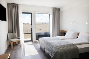 A hotel room with a bed, a chair, a desk, and a TV.
