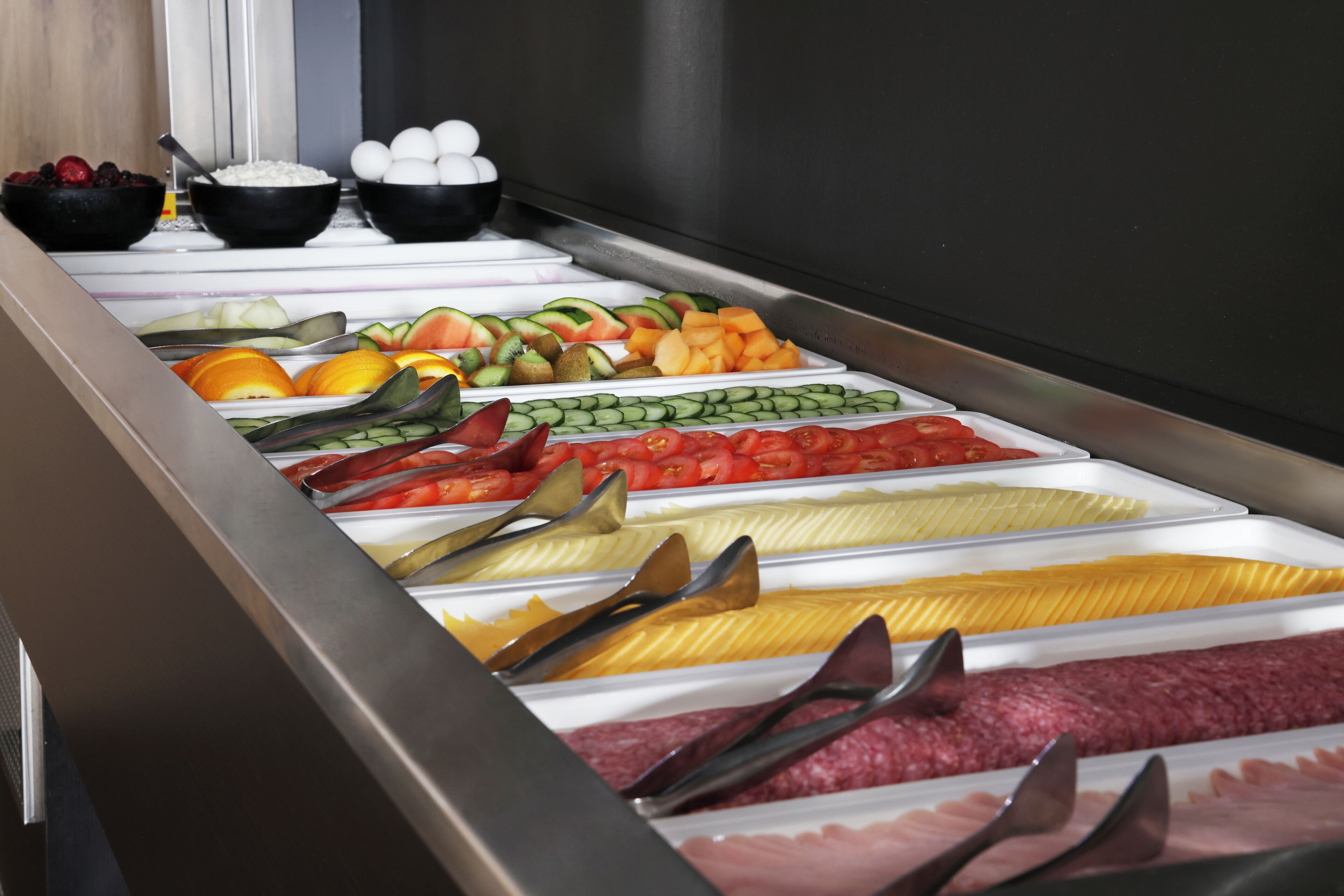 A buffet with various food items including fruits, vegetables, and meats.