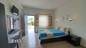 Een slaapkamer met een bed, een bureau, een stoel en een televisie die aan de muur is bevestigd.
