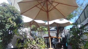Un espacio al aire libre con varias sombrillas, mesas, sillas y plantas en macetas.